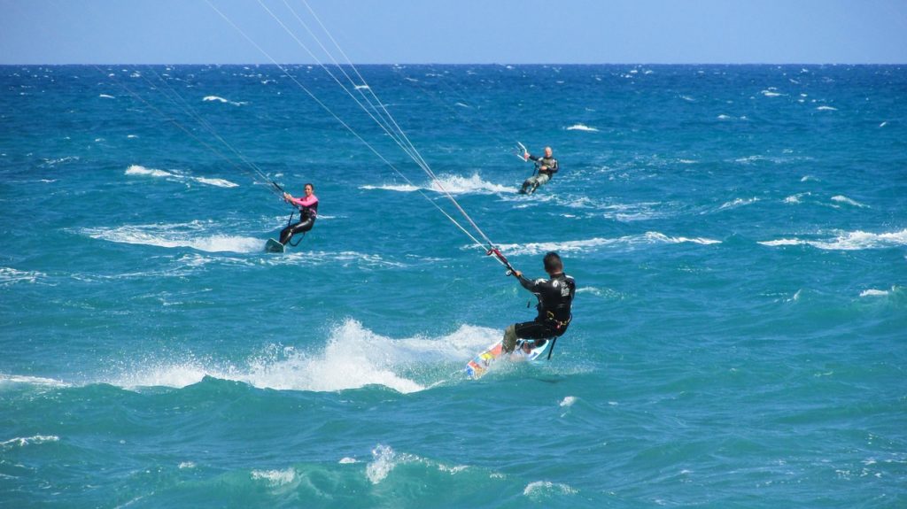 Personas practicando kitesurf en aguas azul turquesa.