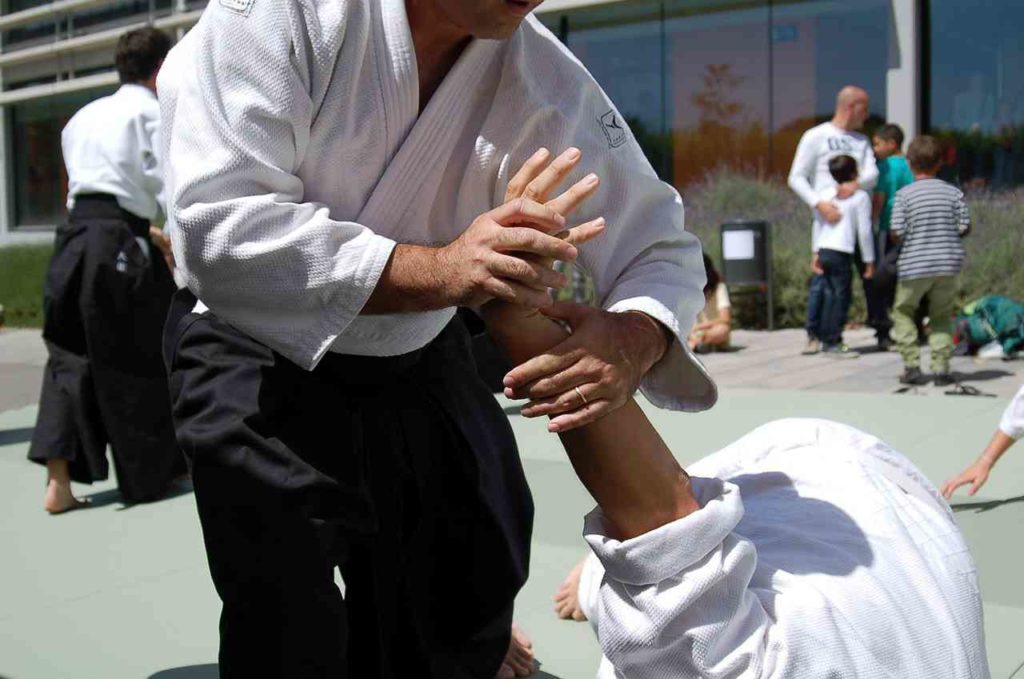 Historia del aikido: hombre sometiendo a otro haciendo uso de técnicas controladas